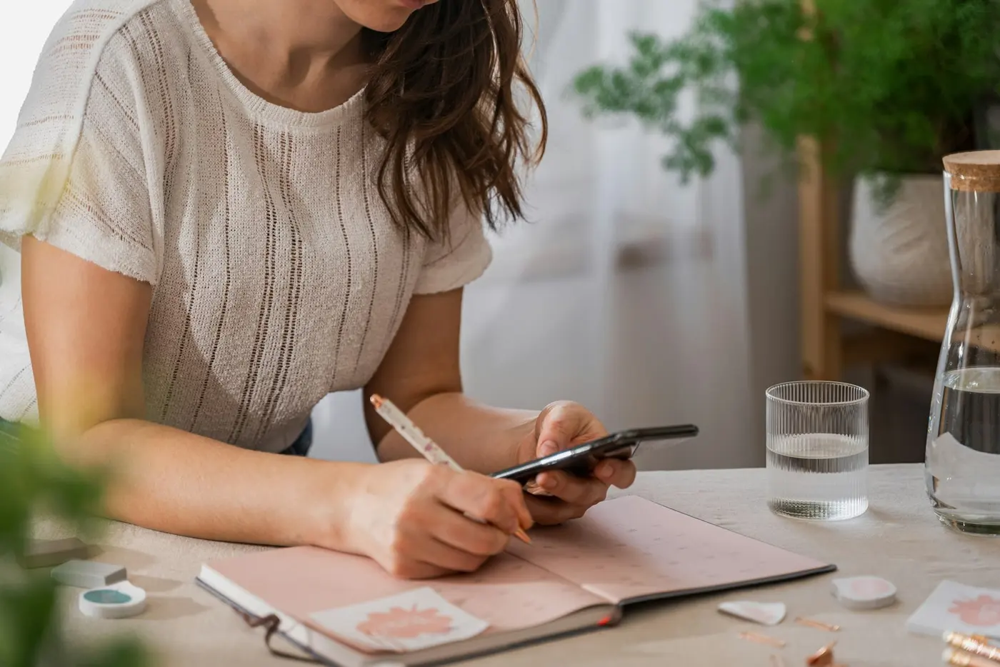 An adviser at a desk making notes beside her phone.